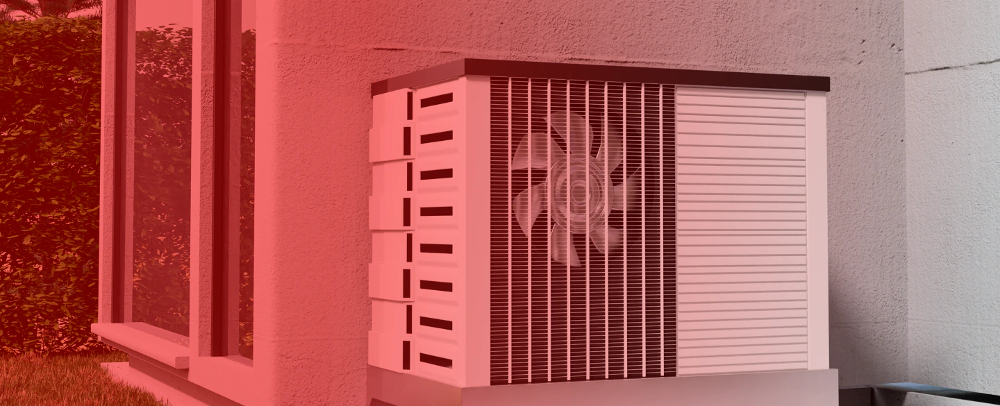 air conditioning box with a black top on a grey wall with bushes in the back